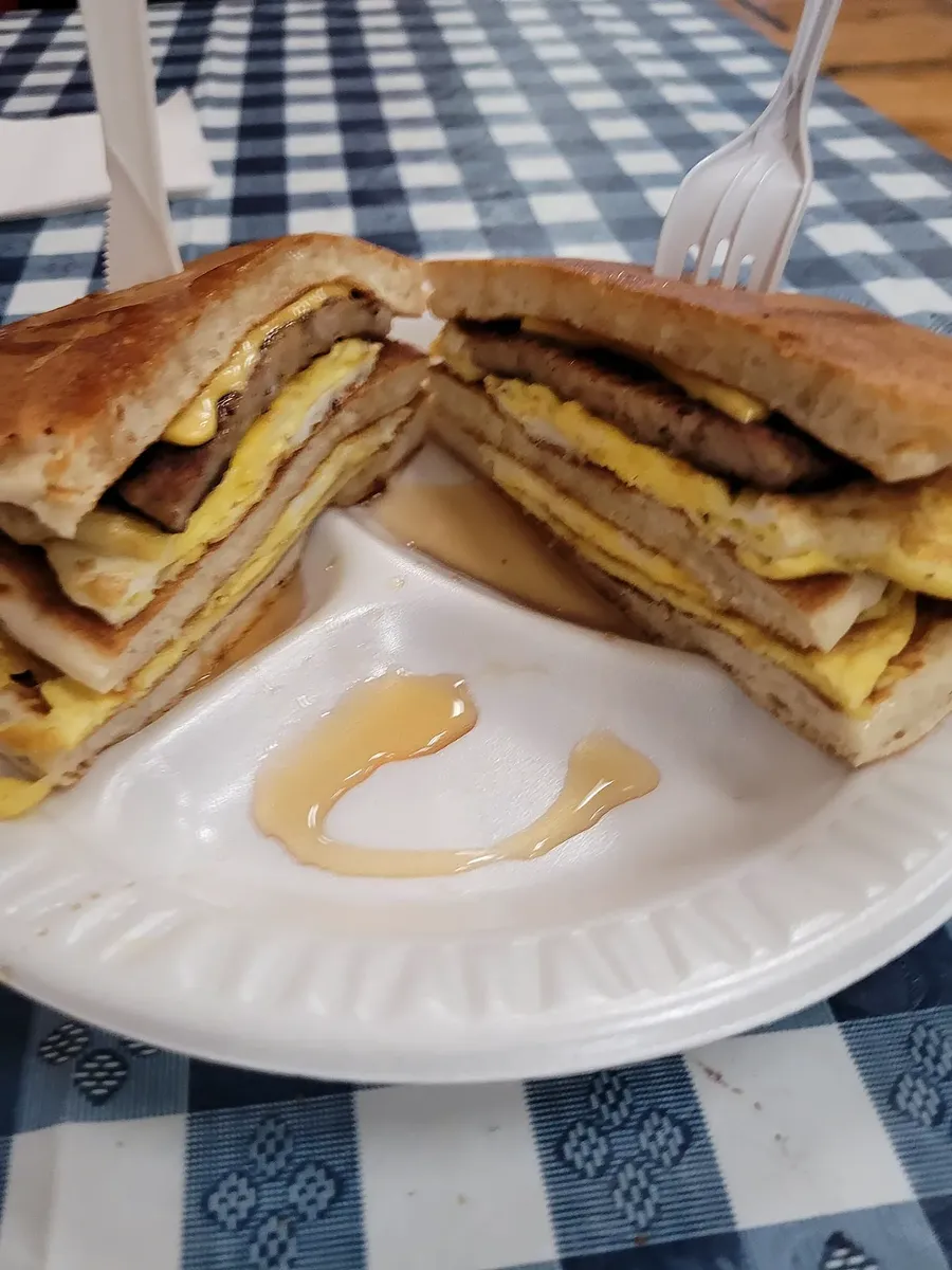 A pancake breakfast sandwich with sausage, egg and cheese