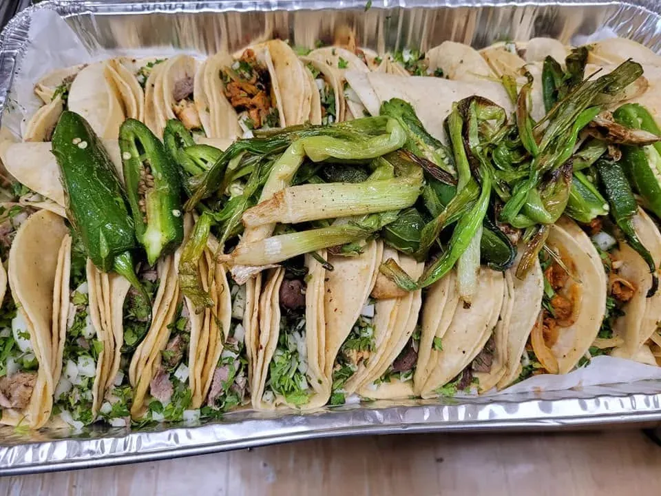 A tray of tacos with grilled scallions and jalapeños