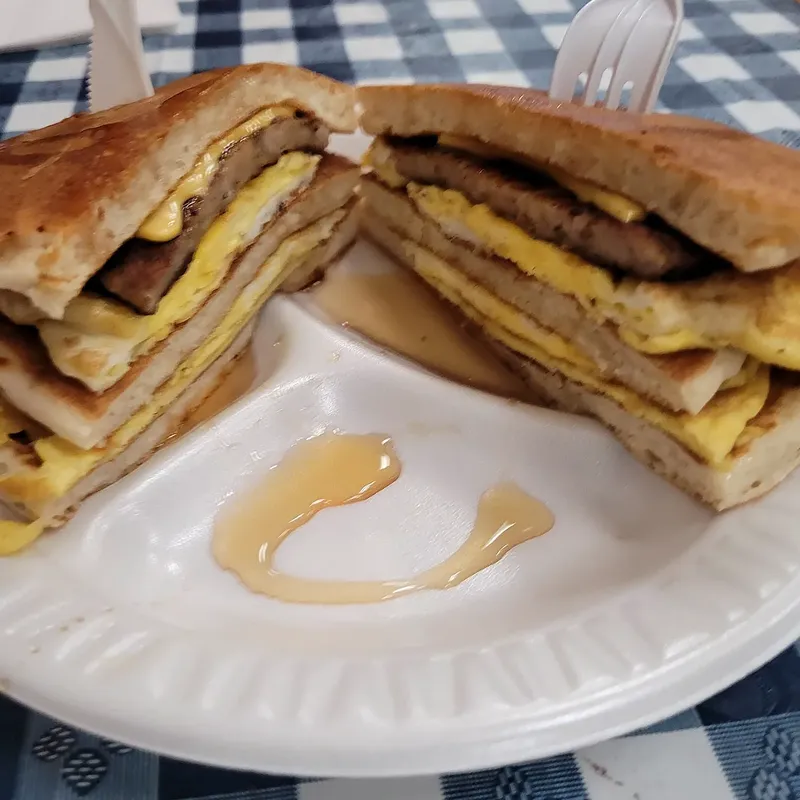 A pancake breakfast sandwich with sausage, egg and cheese