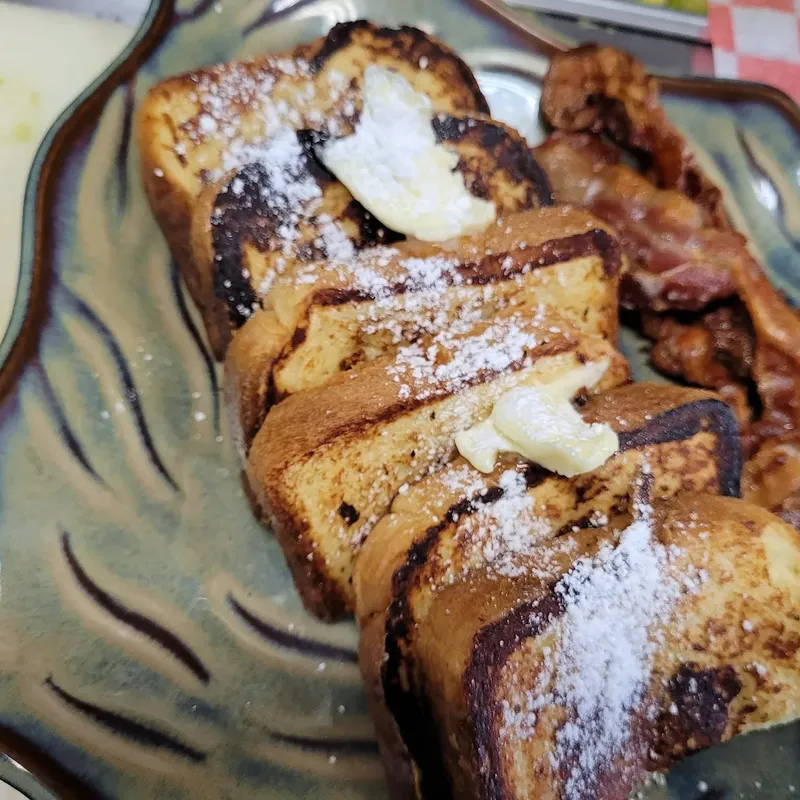 French toast with powdered sugar, butter and bacon